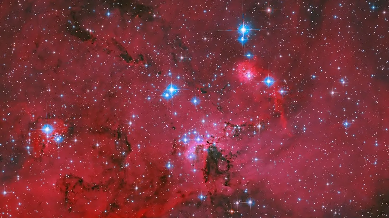 NASA’s Hubble captures a crimson stellar nursery with sparkling blue and white stars